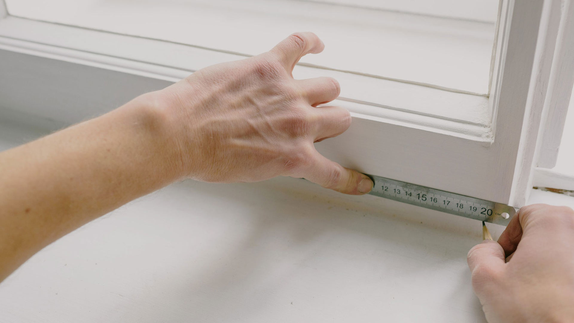 Person measuring a window frame